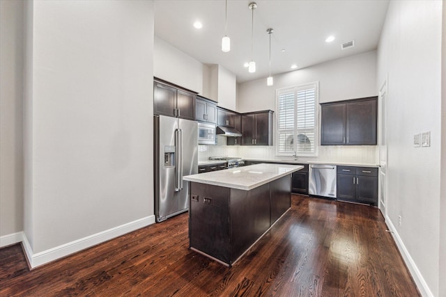 kitchen with dark brown cabinetry, tasteful backsplash, a center island, hanging light fixtures, and appliances with stainless steel finishes