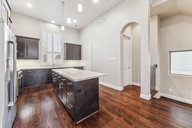 kitchen featuring appliances with stainless steel finishes, pendant lighting, backsplash, a center island, and dark brown cabinets