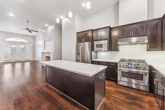 kitchen with hanging light fixtures, premium appliances, dark hardwood / wood-style floors, a kitchen island, and decorative backsplash