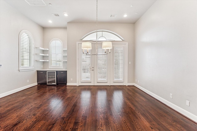 empty room with dark hardwood / wood-style floors, beverage cooler, and french doors