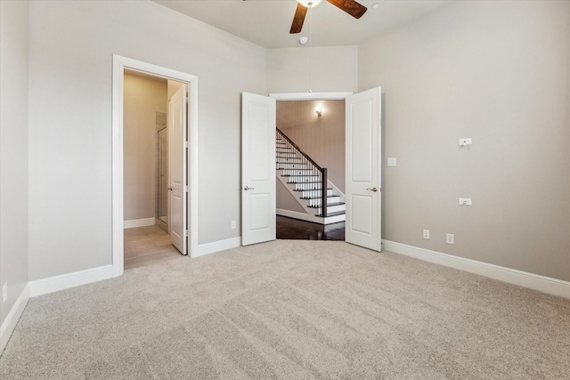 unfurnished bedroom featuring light colored carpet, ceiling fan, and ensuite bath