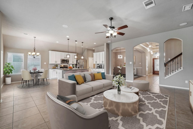 tiled living room with ceiling fan with notable chandelier