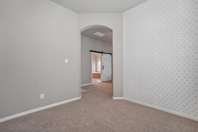 spare room featuring light colored carpet and a barn door