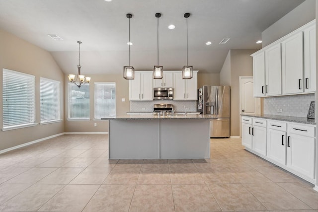 kitchen featuring vaulted ceiling, a kitchen island with sink, appliances with stainless steel finishes, and decorative light fixtures