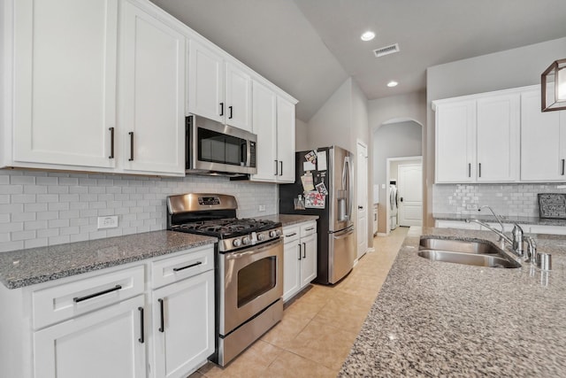 kitchen featuring light tile patterned floors, backsplash, white cabinets, and stainless steel appliances