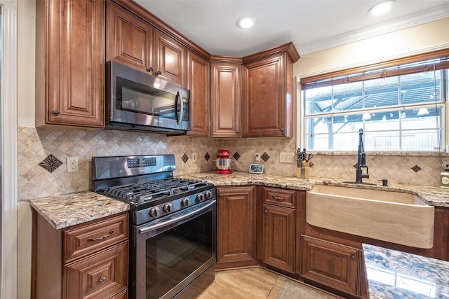 kitchen with tasteful backsplash, sink, light tile patterned floors, light stone counters, and stainless steel appliances