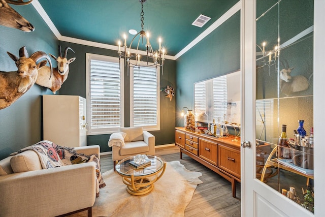 living area with a notable chandelier, light hardwood / wood-style flooring, and ornamental molding