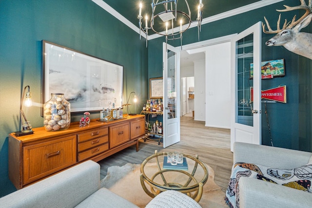 living room featuring crown molding, a chandelier, and light wood-type flooring