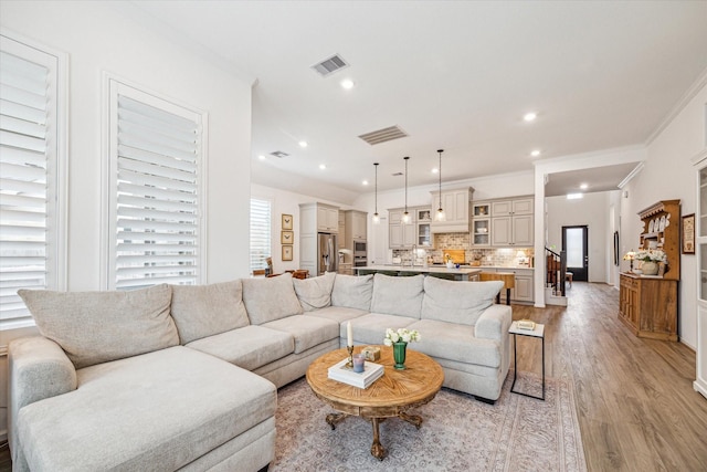 living room featuring light hardwood / wood-style floors, sink, and crown molding