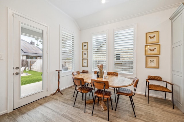 dining room featuring light wood-type flooring, vaulted ceiling, a healthy amount of sunlight, and ornamental molding