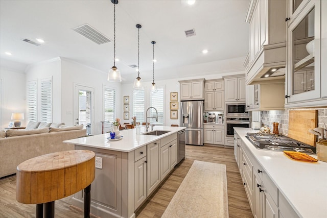 kitchen featuring decorative backsplash, sink, pendant lighting, an island with sink, and stainless steel appliances