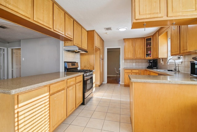 kitchen featuring kitchen peninsula, appliances with stainless steel finishes, decorative backsplash, and light tile patterned flooring