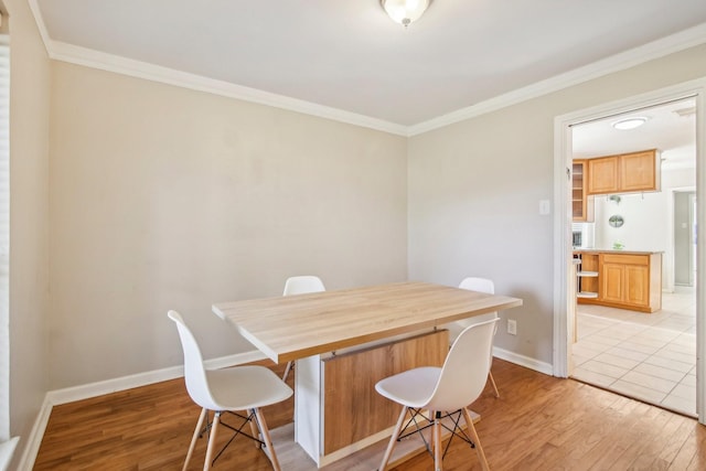 dining room with ornamental molding and light hardwood / wood-style floors