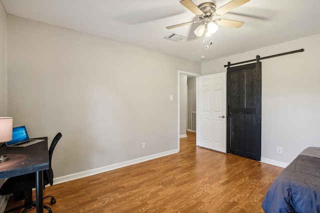 office space featuring ceiling fan, a barn door, and hardwood / wood-style floors