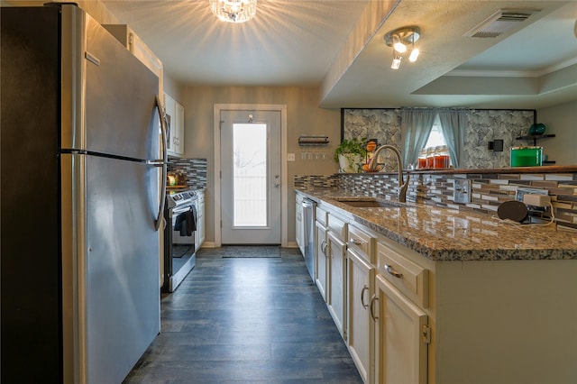 kitchen featuring sink, light stone counters, appliances with stainless steel finishes, plenty of natural light, and decorative backsplash