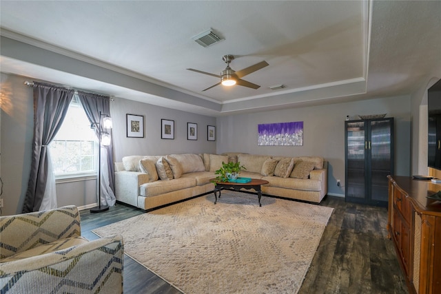 living room with a raised ceiling, crown molding, dark hardwood / wood-style floors, and ceiling fan