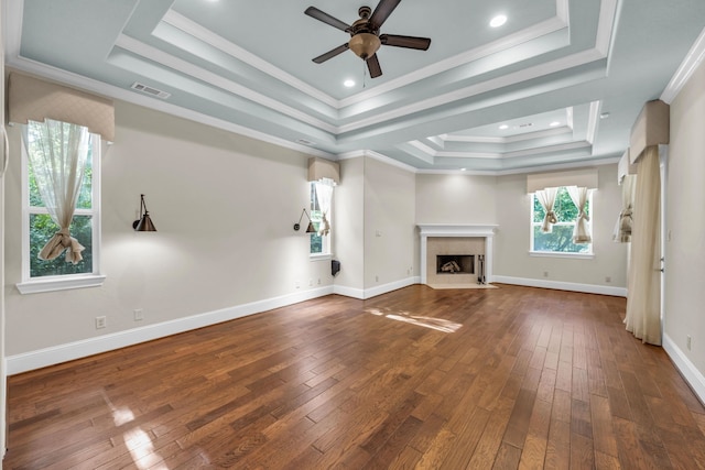 unfurnished living room with a wealth of natural light, a tray ceiling, and ornamental molding