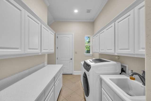 laundry room with cabinets, washing machine and clothes dryer, sink, light tile patterned floors, and crown molding