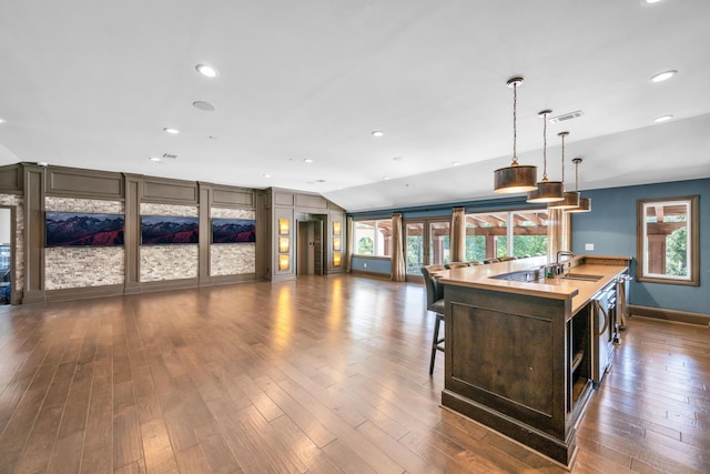 kitchen with pendant lighting, dark hardwood / wood-style flooring, sink, a center island with sink, and lofted ceiling