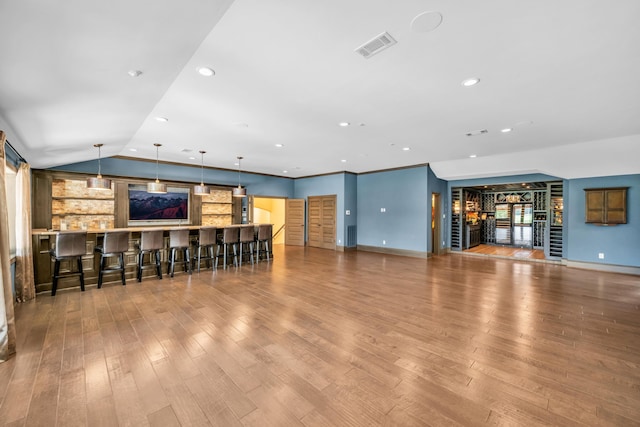 living room with built in shelves, indoor bar, light hardwood / wood-style floors, and lofted ceiling