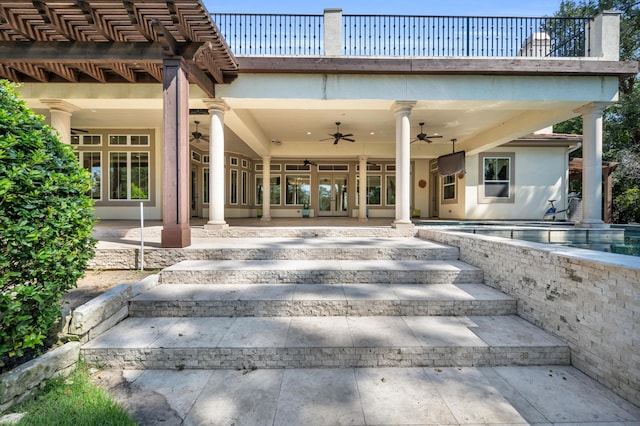 view of exterior entry featuring a balcony, ceiling fan, and a patio