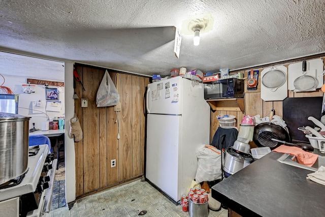 kitchen with a textured ceiling, white refrigerator, and range with gas stovetop