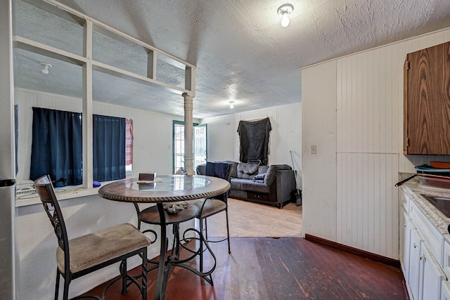 dining space with hardwood / wood-style flooring, a textured ceiling, and wood walls