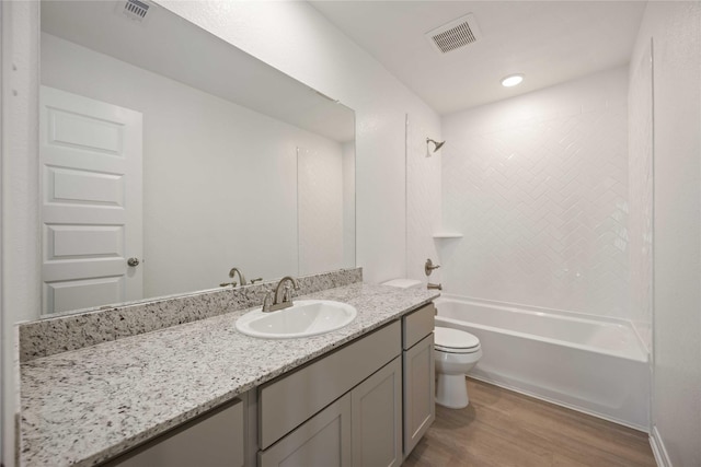 full bathroom featuring vanity, toilet, tiled shower / bath combo, and hardwood / wood-style floors