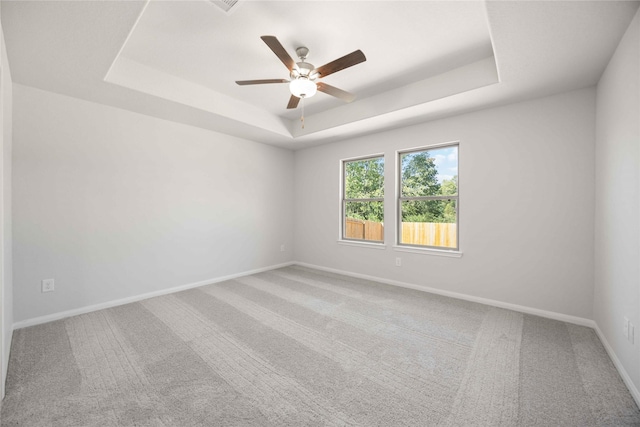 carpeted spare room featuring ceiling fan and a raised ceiling