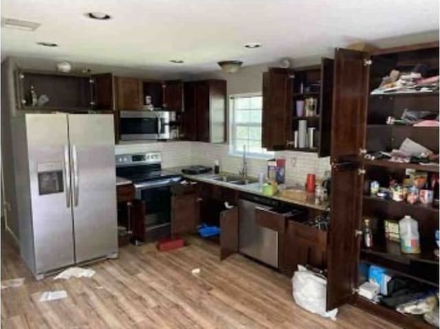 kitchen with sink, light wood-type flooring, tasteful backsplash, stainless steel appliances, and dark brown cabinetry