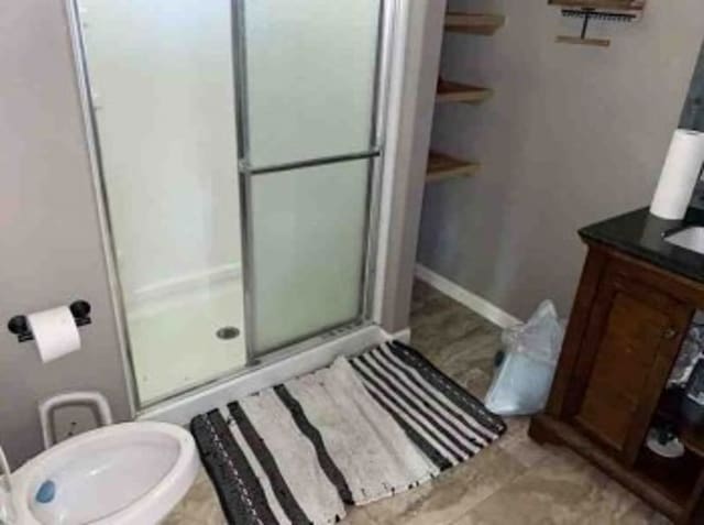 bathroom featuring a shower with shower door and vanity