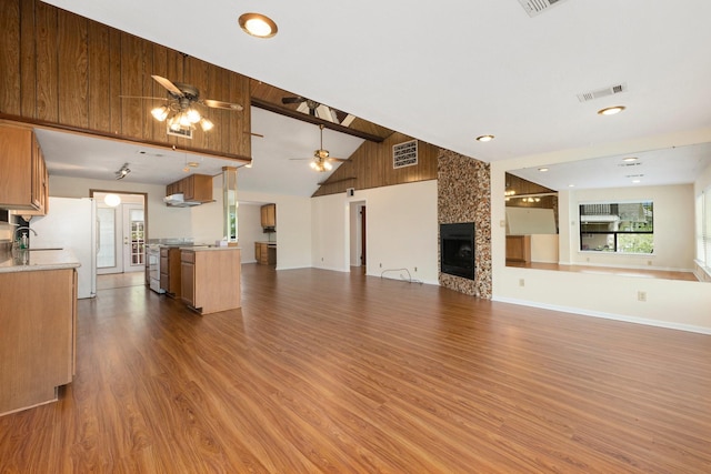 unfurnished living room featuring ceiling fan, hardwood / wood-style floors, high vaulted ceiling, and a fireplace