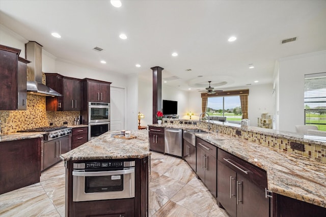 kitchen featuring crown molding, appliances with stainless steel finishes, sink, light stone countertops, and a kitchen island