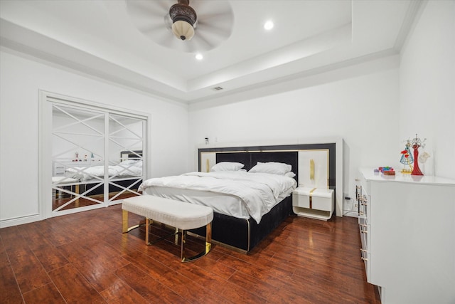 bedroom featuring dark wood-type flooring, ceiling fan, and a raised ceiling