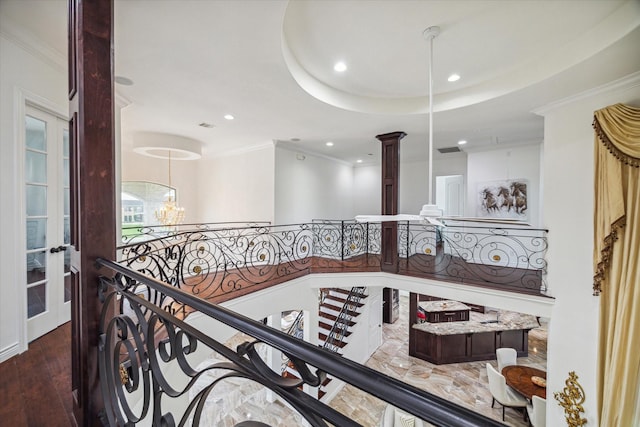 hall featuring dark wood-type flooring, ornate columns, a raised ceiling, a chandelier, and crown molding