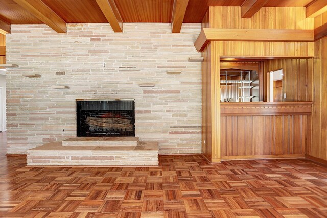 details with a fireplace, wooden ceiling, wooden walls, and beamed ceiling