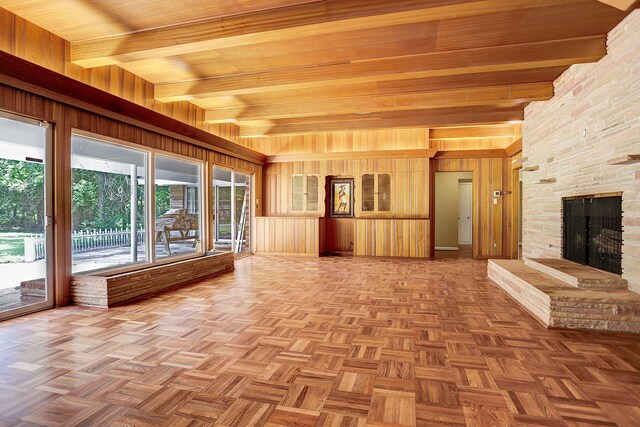 interior space with parquet flooring, beamed ceiling, wood walls, and a fireplace