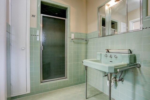 bathroom with sink, tile walls, and a shower with door