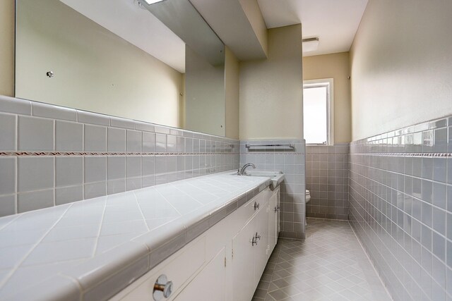 bathroom featuring vanity, toilet, tile walls, and tile patterned flooring