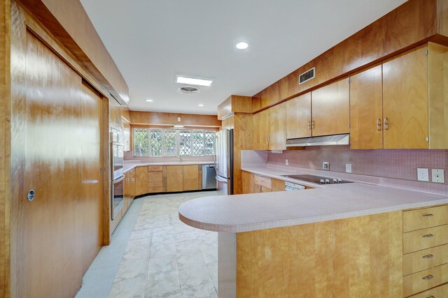 kitchen with appliances with stainless steel finishes, sink, backsplash, kitchen peninsula, and light tile patterned flooring