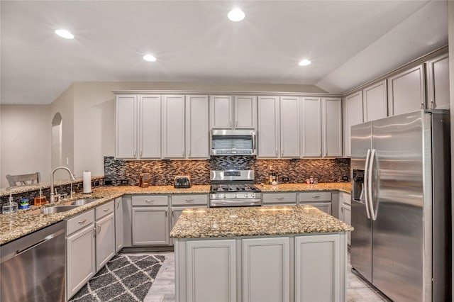 kitchen featuring kitchen peninsula, sink, light stone countertops, and stainless steel appliances