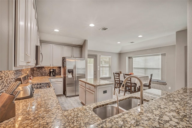 kitchen featuring light stone countertops, sink, a kitchen island, stainless steel appliances, and lofted ceiling