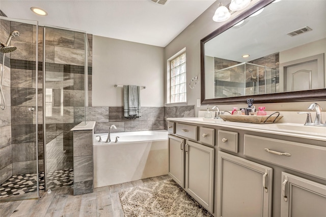 bathroom with hardwood / wood-style floors, vanity, tile walls, and plus walk in shower