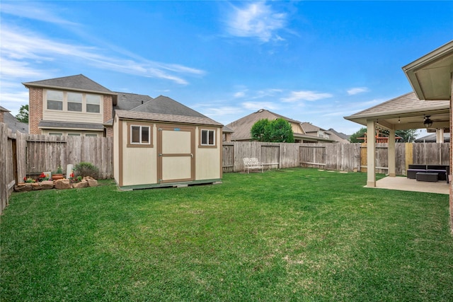 view of yard featuring a patio area, ceiling fan, and a storage unit