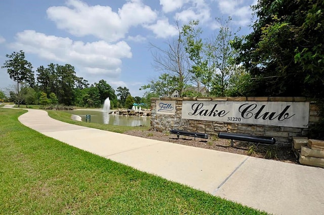 community / neighborhood sign with a water view and a lawn