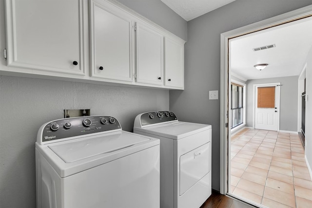 clothes washing area with light tile patterned floors, cabinets, and independent washer and dryer