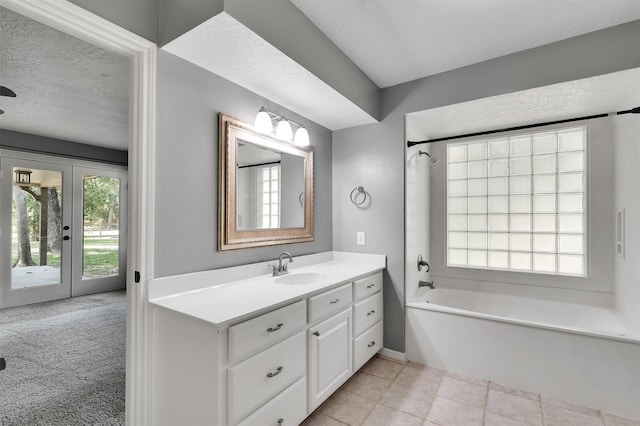 bathroom featuring a washtub, a textured ceiling, french doors, and vanity