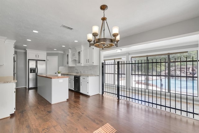 kitchen with appliances with stainless steel finishes, sink, white cabinetry, a center island, and butcher block counters