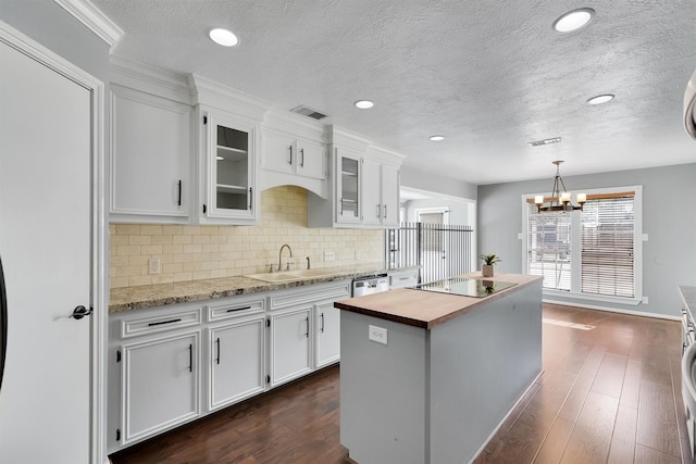 kitchen with white cabinets, black electric stovetop, butcher block counters, and a kitchen island