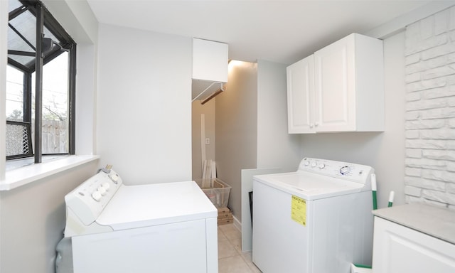 clothes washing area with cabinets, washing machine and dryer, and light tile patterned flooring